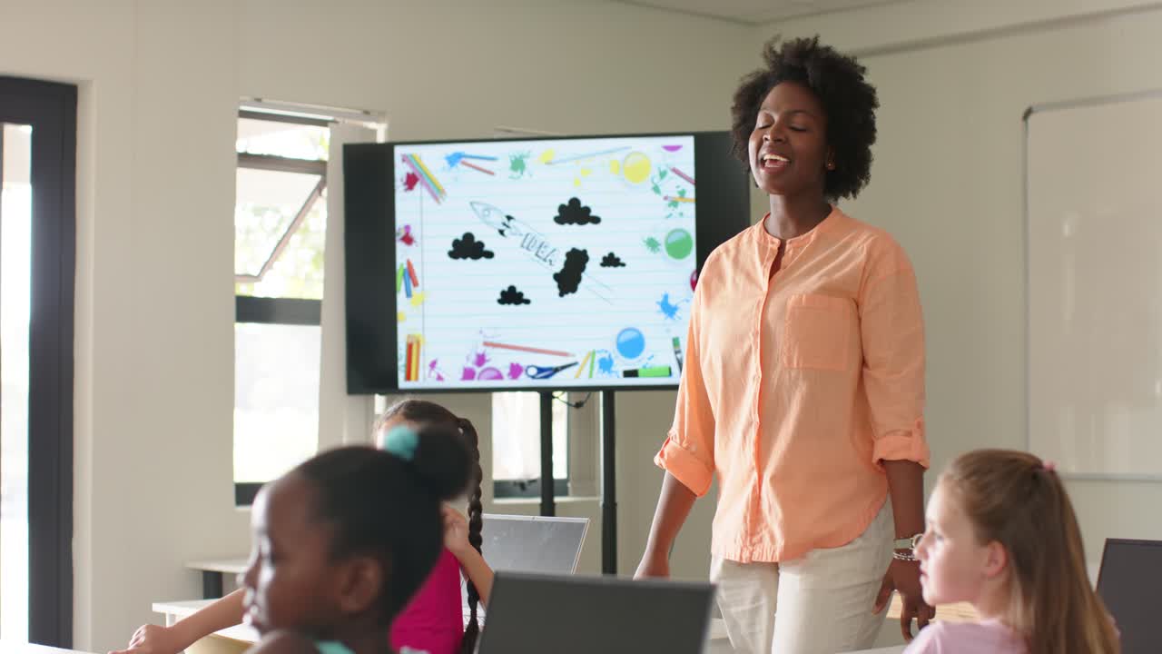 African American teacher entering front in peach top, gesturing at screen and drawing raised hand
