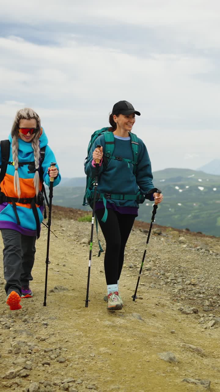 Due donne che fanno escursioni su un sentiero di montagna con bastoncini da trekking