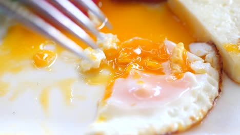 close up of a fried egg with a fork and knife on a plate