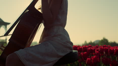 closeup unknown girl playing cello in blooming summer garden in sun reflection.