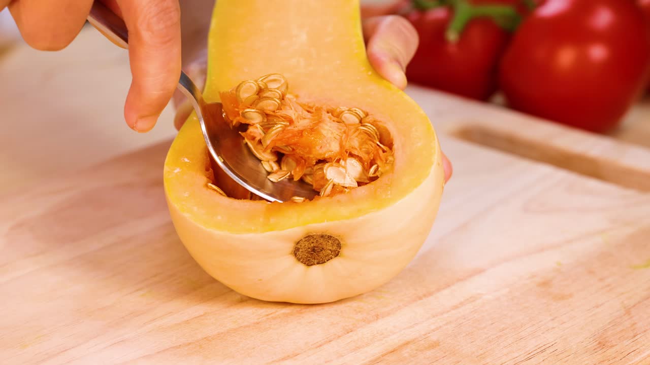 Scooping seeds from a halved butternut squash