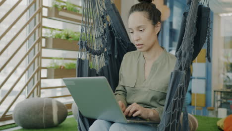 woman working on laptop in a hammock in a modern office