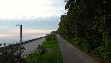 Antenne,-Die-Während-Des-Sonnenuntergangs-über-Den-Esplanade-Gehweg-Mit-Bäumen-Im-Küstenboulevard-Von-Gdynia-Fliegt