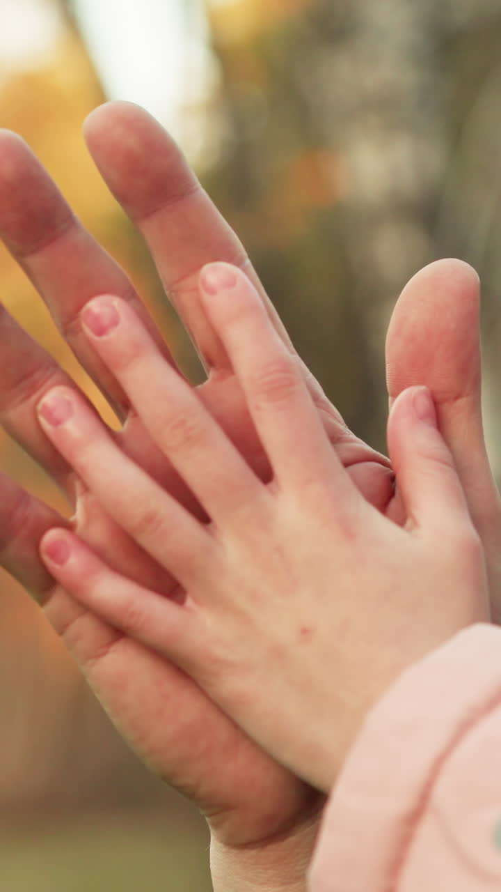 어린아이의 손이 어른의 손에 부드럽게 누워있는 감동적인 순간의 클로즈업, 신뢰, 연결 및 따뜻함을 상징합니다.