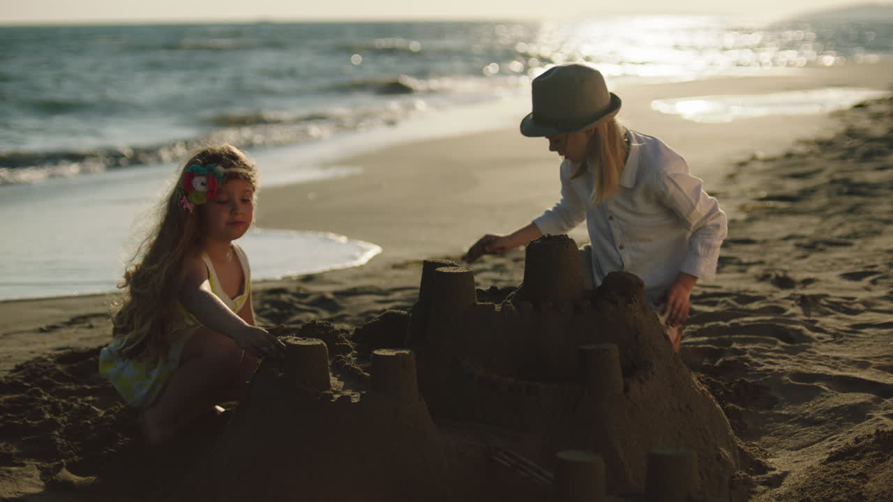 해가 지면 해변에 모래 성을 짓는 아이들