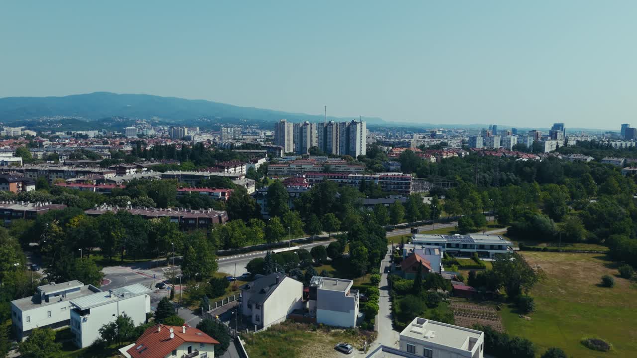 aerial - Zagreb cityscape with mix of tall buildings and low-rise homes backed by distant hills