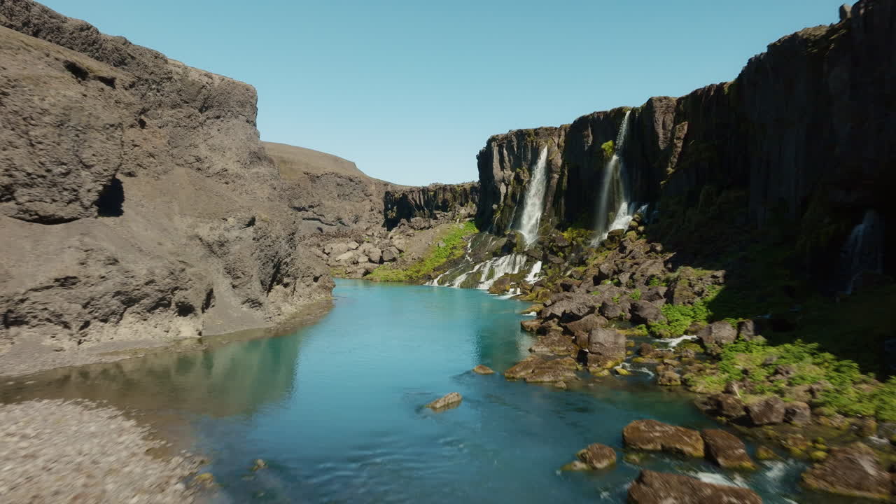 Low-altitude drone flight through Sigöldugljúfur canyon with waterfalls, stream