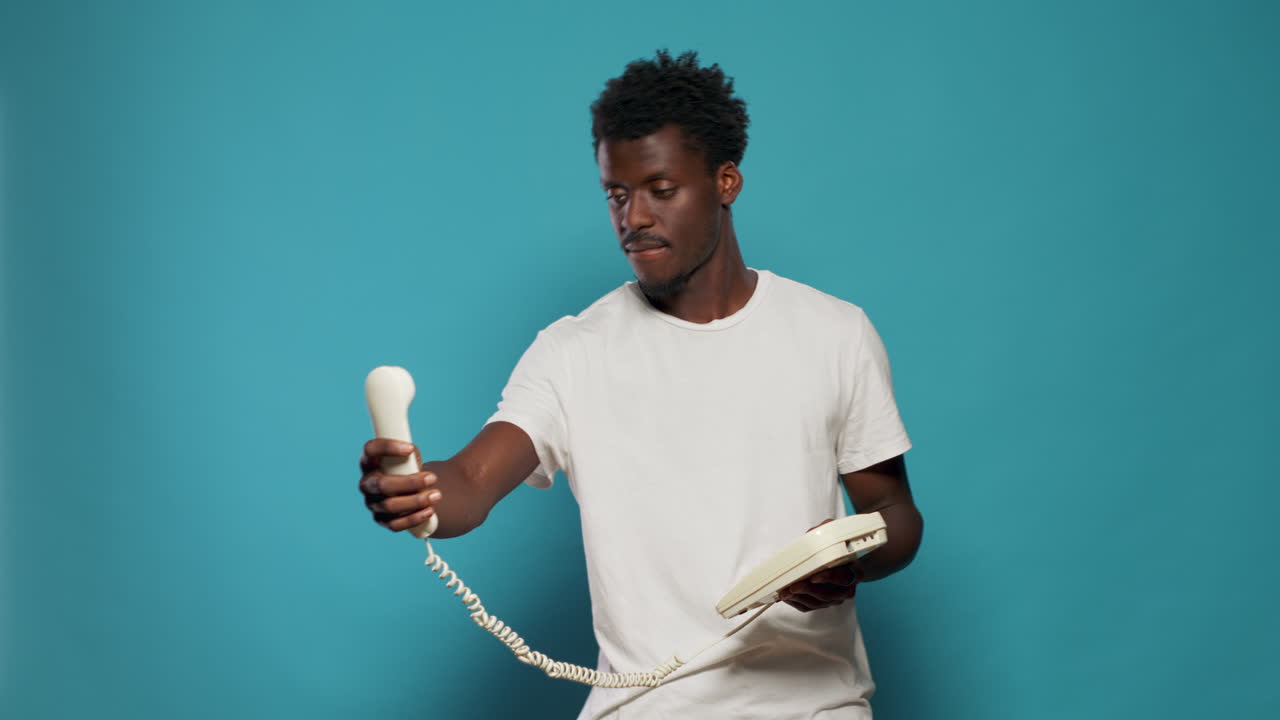 Playful man joking about taking selfies with retro landline phone