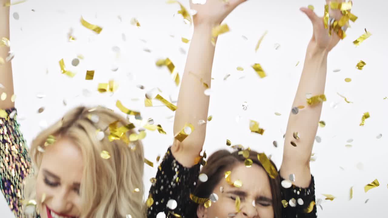 두 여자가 떨어지는 콘페티 사이에서 춤을 추고 있습니다.