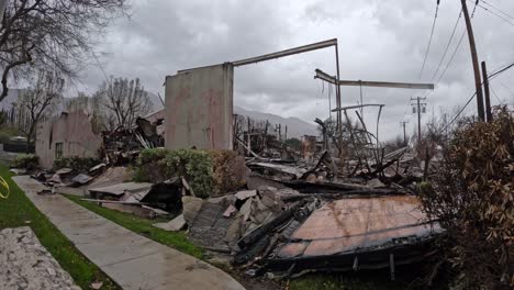 smoke rises from charred ruins as rain falls over blackened earth. embers glow, puddles reflect destruction. a powerful scene for news, documentaries, and climate awareness.