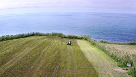 Tractor-Cortando-Hierba-En-El-Borde-Del-Acantilado,-Azores,-Antena-Giratoria