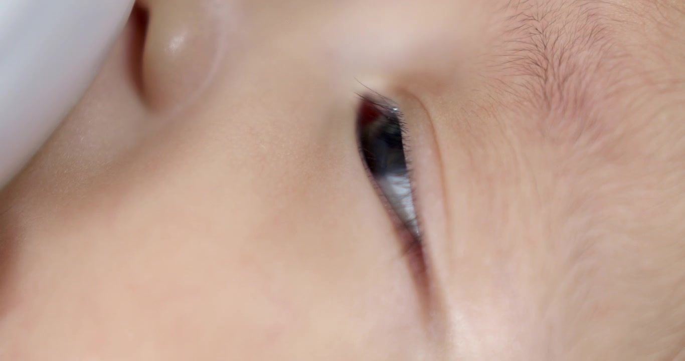 Catturato in primo piano lo sguardo concentrato di una bambina durante l'allattamento con il biberon. Un momento tenero che mostra la connessione tra nutrimento, attenzione e gli elementi chiave della crescita e dello sviluppo precoce.