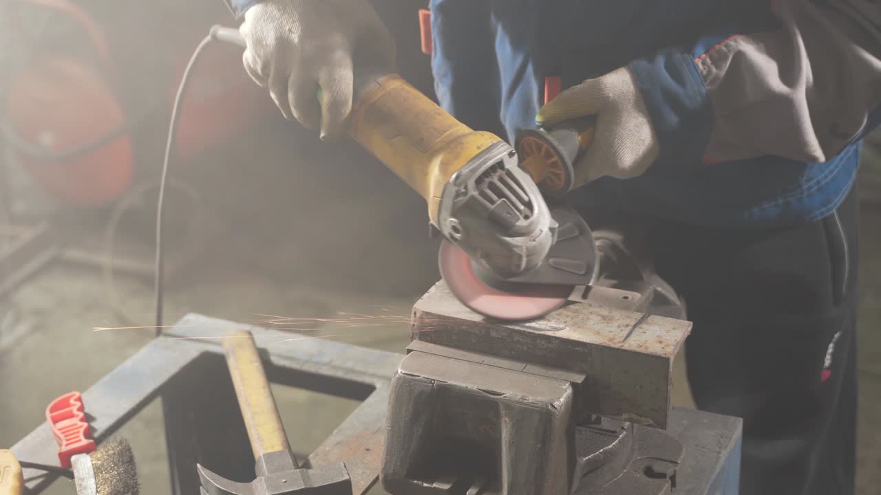 cerrajero en ropa especial y gafas de protección trabaja en la producción. procesamiento de metales con molienda angular. chispas en la metalurgia