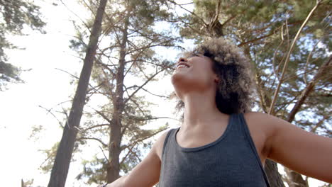 A-young-biracial-woman-with-curly-hair-smiles-outdoors