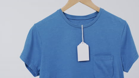 video de camiseta azul con etiqueta en el colgador y espacio de copia en fondo blanco