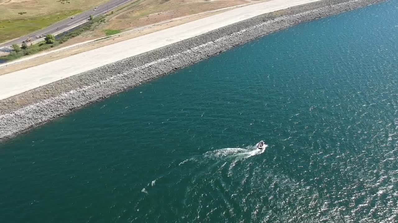 아래에서 운전하는 자동차와 함께 제방 근처의 호수에서 즐거운 시간을 보내는 보트