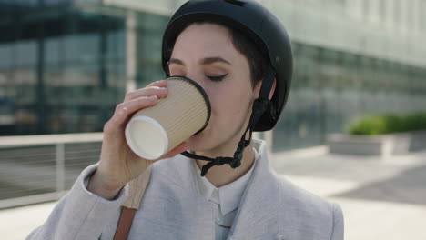 close up portrait of beautiful young business woman intern wearing safety helmet drinking coffee ready to leave work