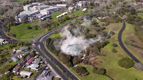 hot water pool in kuirau park and rotorua hospital building aerial reveal of cityscape on lakefront