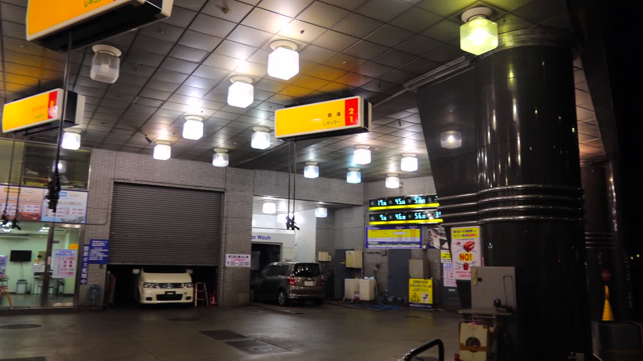 Japanese Shell petrol station with petrol pumps hanging from the ceiling, gas station in Tokyo city Japan, 4K panning left