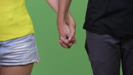 una pareja de jóvenes tomados de la mano.