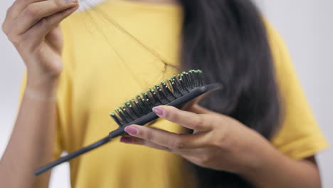 crop view of an unrecognisable woman brushing her hair with comb and removing lost hair from the comb, focus on foreground.