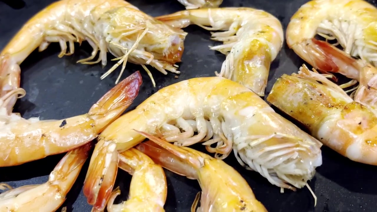 Nærbillede af friske rejer, der syder på en varm grillpande, med fokus på saftig fisk og skaldyr, stigende damp og lækre grillede smagsoplevelser i en madlavningsscene
