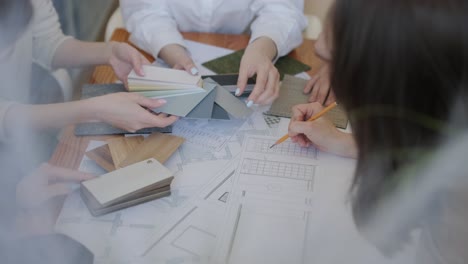 a collaborative design meeting in action, with team members selecting materials and colors, consulting floor plans, and engaging in creative decision-making for an interior design project.