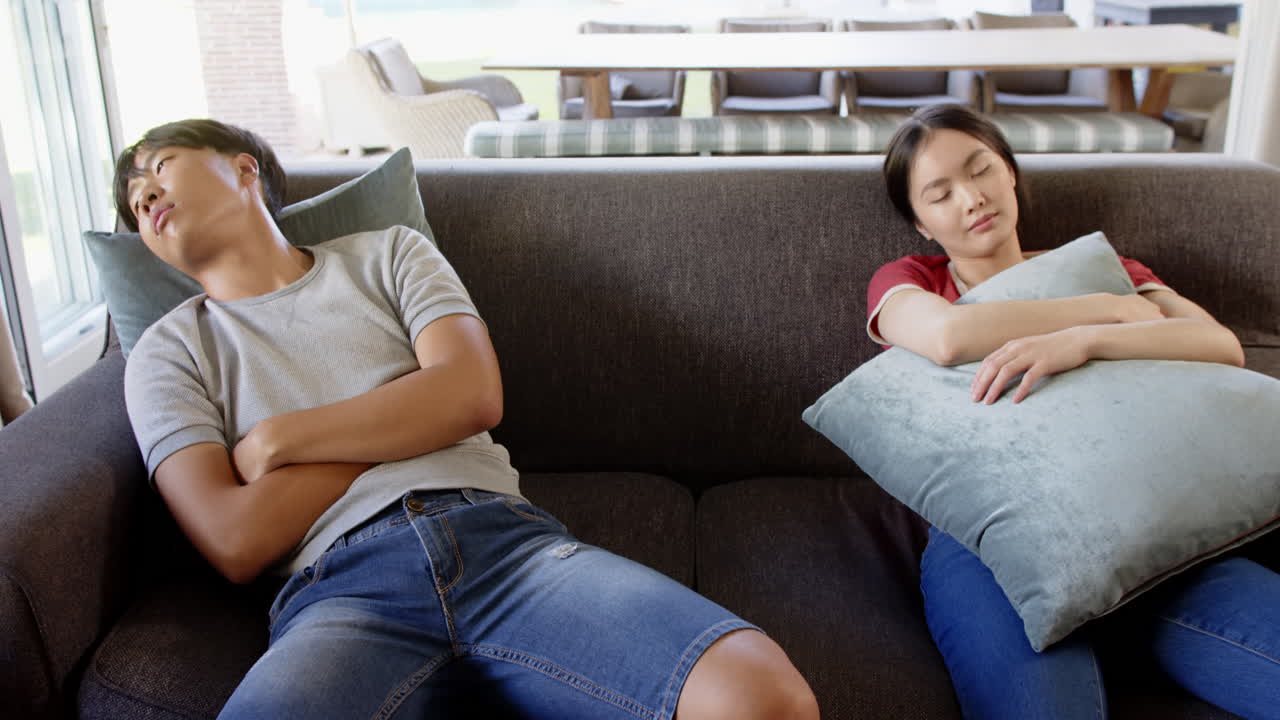 Resting on couch, Asian man and woman napping with pillows in living room
