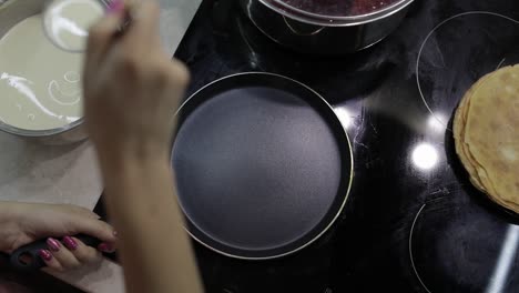 el proceso de cocinar panqueques caseros. mujer vierte la masa de panqueques en la sartén