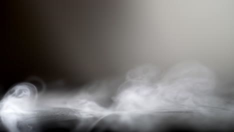 slow motion fog smoke wispy spins from side spread over leather surface, grey background