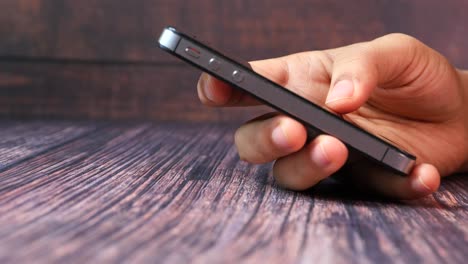 hand holding a smartphone on a wooden table