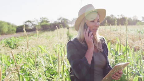 Video-of-happy-caucasian-woman-using-tablet-and-smartphone-in-field-on-sunny-day