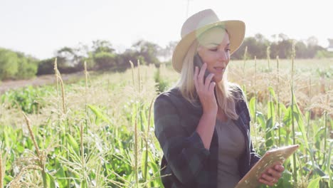 video de una mujer caucásica feliz usando una tableta y un teléfono inteligente en el campo en un día soleado