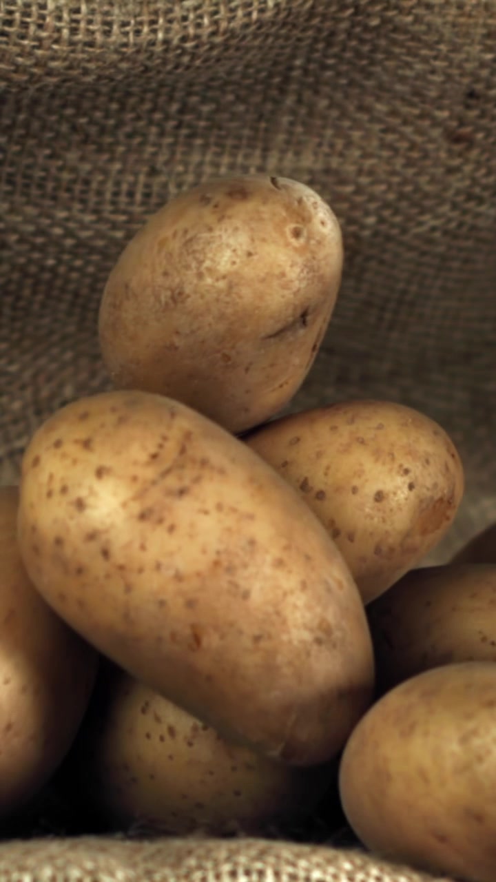 Patate crude fresche che cadono su un sacco di iuta