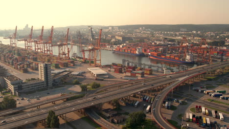toma aérea cinematográfica del puerto industrial y el tráfico en la carretera en gdynia durante el amanecer dorado