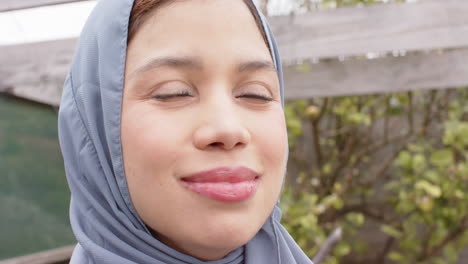 portrait of smiling biracial woman in hijab with copy space, slow motion