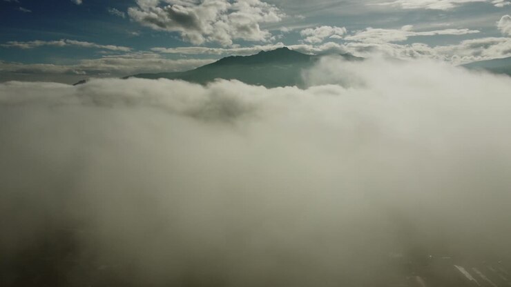 Aerial view of Pasochoa volcano shrouded in thick white fog on a sunny day