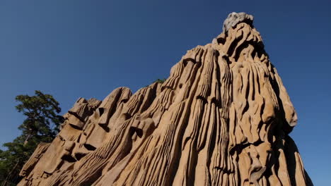 close-up of a unique eroded rock formation with deep grooves against a clear blue sky