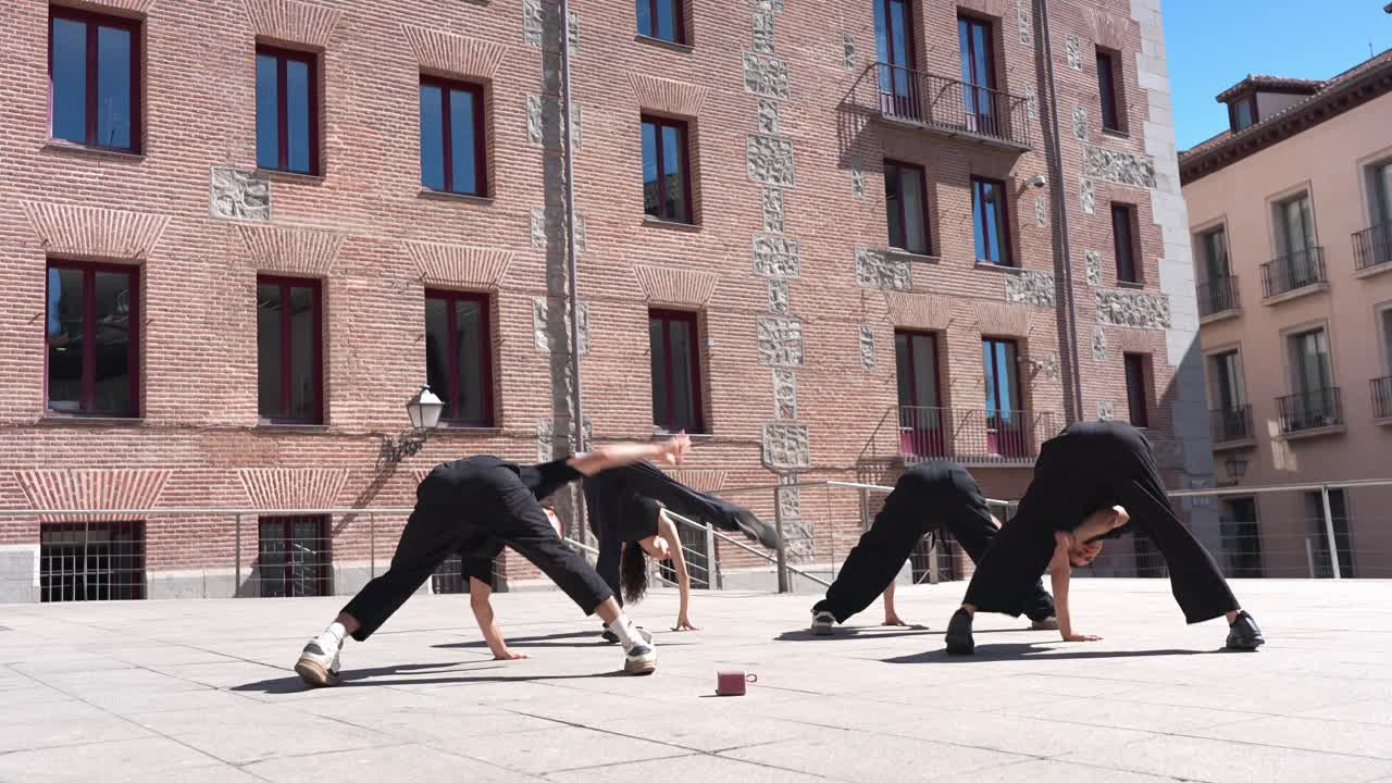 Group of Young Dancers Performing Synchronized Choreography in Urban Plaza