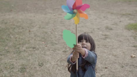 adorable chica latina jugando con abanico de papel en el parque