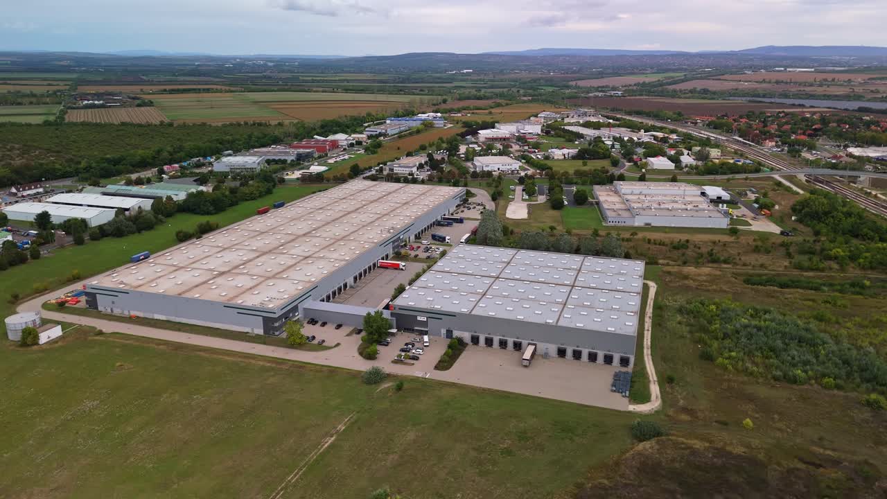 Aerial view of an industrial park on the outskirts of Százhalombatta, Hungary, with loading trucks and hangar buildings along the road 6