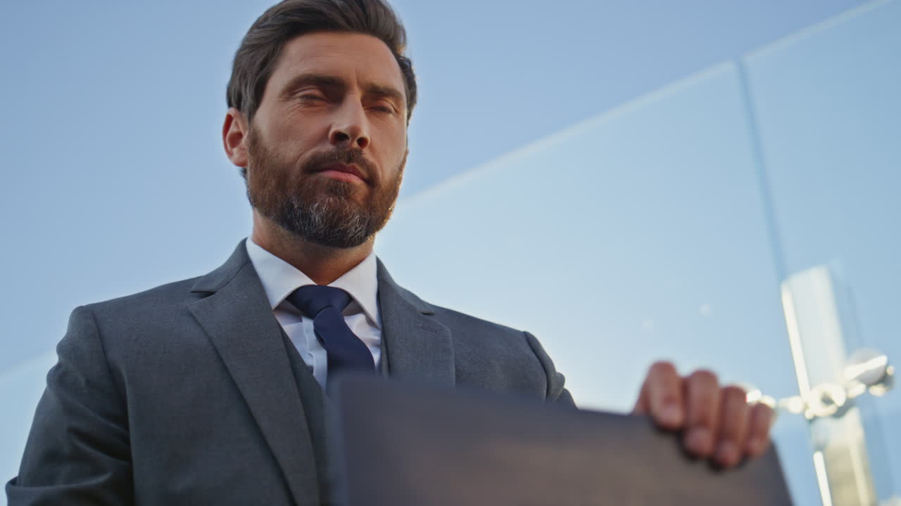 Primo piano di un professionista della finanza che guarda lo schermo del laptop con il cielo blu. Lavoratore aziendale che conclude la giornata.