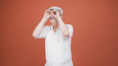 un anciano con binoculares mirando hacia otro lado.