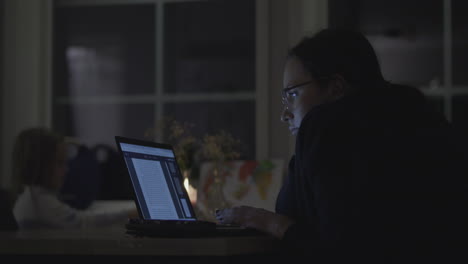 single mother studying or working late at night daughter in background