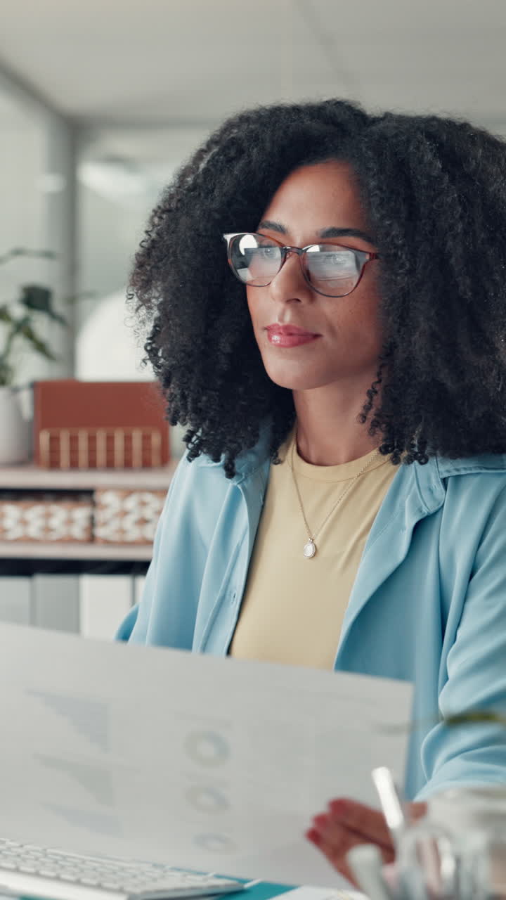Donna concentrata che lavora al computer e rivede documenti in ufficio