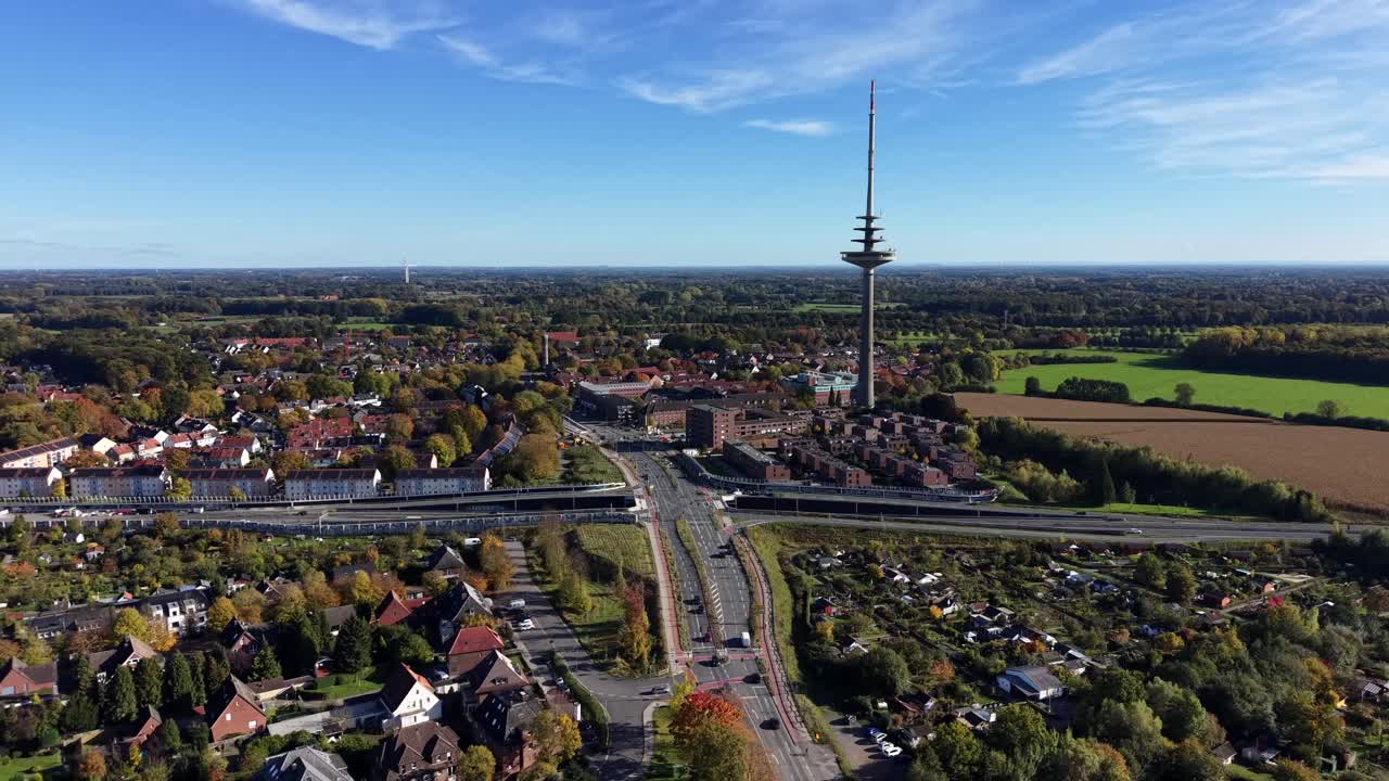 Driving cars on road and interstate of american town in autumn season. Telecommuniction tower in suburb with rural countryside fields and suburbia neighborhood. Aerial wide shot. Sunny day in fall