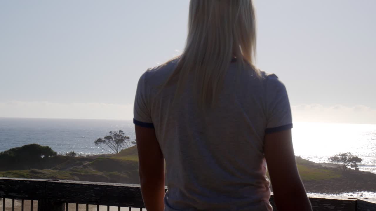 Female walking onto balcony platform overlooking ocean sea view landscape