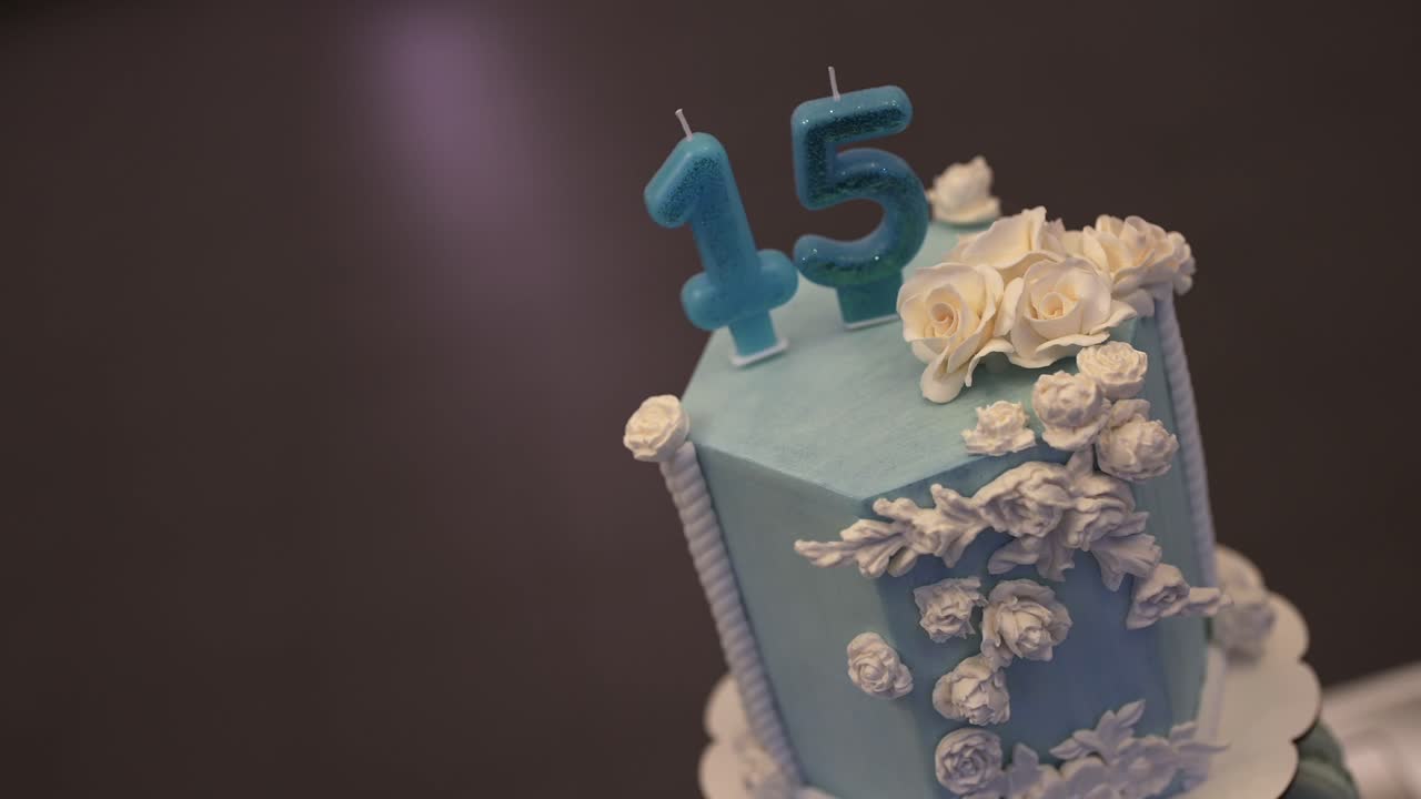 Close-up view of sweet fifteen blue birthday cake and white floral decorations