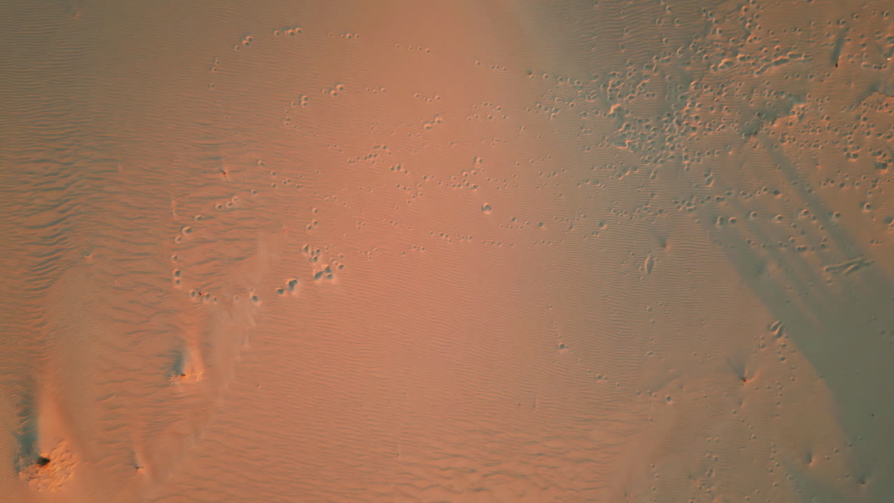 Aerial view sand footprints traversing textured dunes at sunset. Dusk nature
