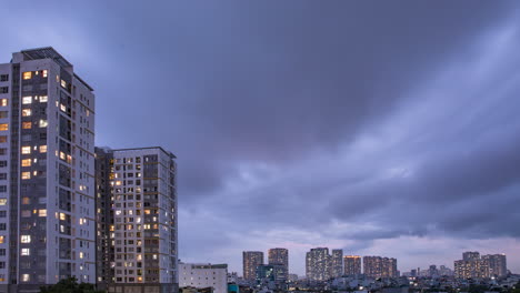 day to night time lapse in densely populated urban area with artificial electric lights coming on in illuminated buildings